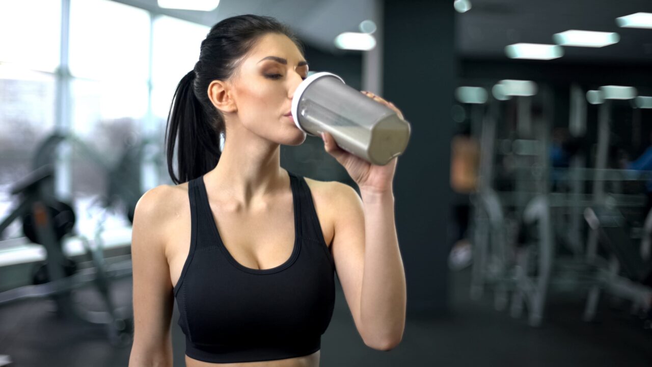 donna che assume proteine in palestra per la massa muscolare