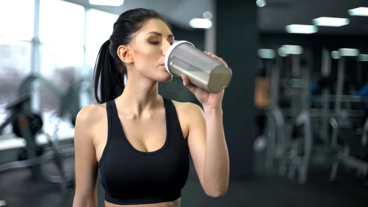 donna che assume proteine in palestra per la massa muscolare