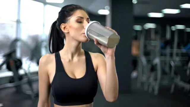 donna che assume proteine in palestra per la massa muscolare